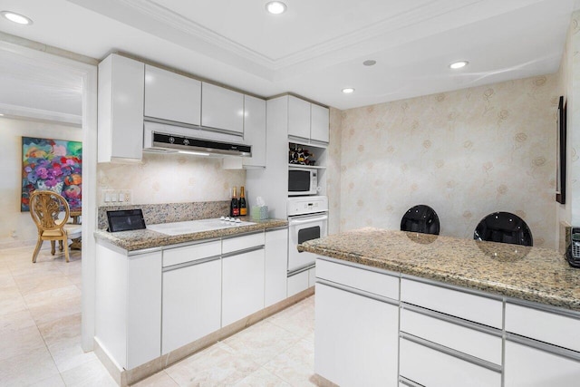 kitchen featuring white appliances, light stone counters, decorative backsplash, white cabinetry, and ornamental molding