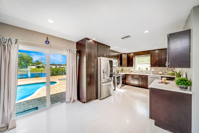 kitchen with stainless steel appliances, dark brown cabinetry, and backsplash