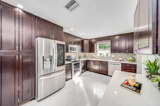 kitchen with sink, light stone counters, tasteful backsplash, and appliances with stainless steel finishes