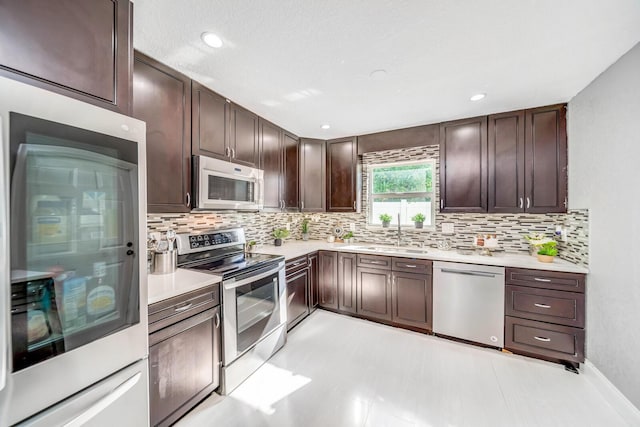 kitchen featuring sink, dark brown cabinetry, appliances with stainless steel finishes, and decorative backsplash