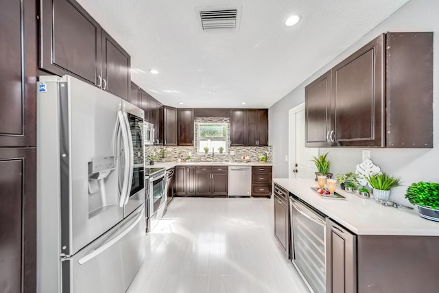 kitchen with dark brown cabinets, decorative backsplash, wine cooler, and stainless steel appliances