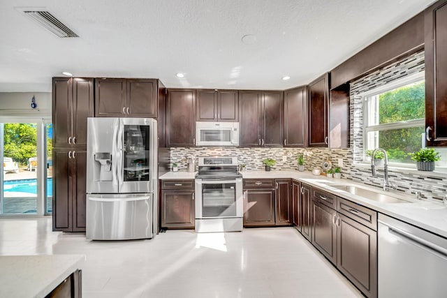 kitchen with sink, backsplash, appliances with stainless steel finishes, and dark brown cabinets