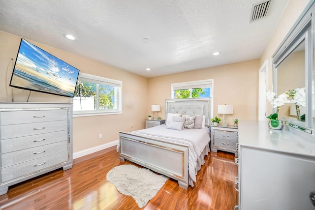 bedroom with a textured ceiling and light hardwood / wood-style flooring