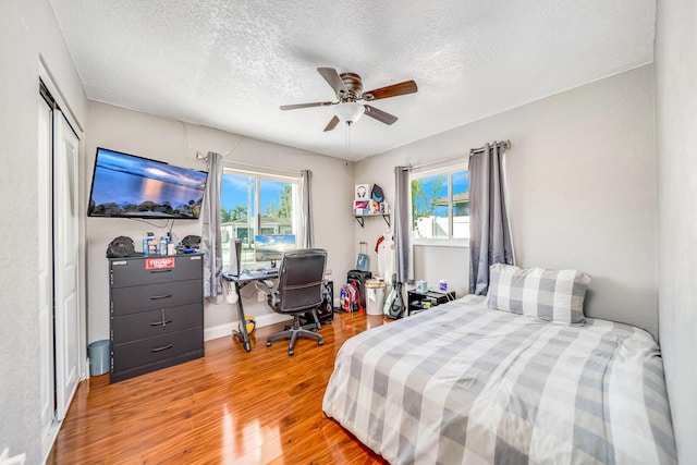 bedroom featuring a closet, ceiling fan, multiple windows, and hardwood / wood-style flooring