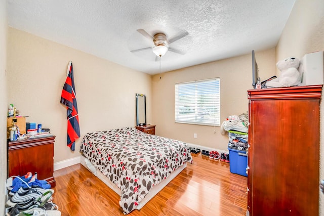 bedroom with hardwood / wood-style flooring, a textured ceiling, and ceiling fan