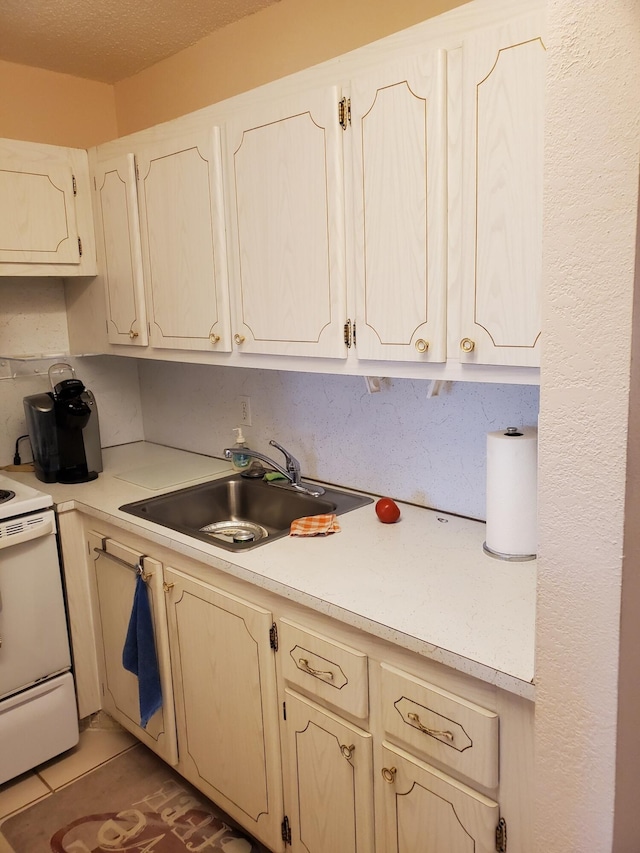 kitchen with stove, tile patterned flooring, and sink