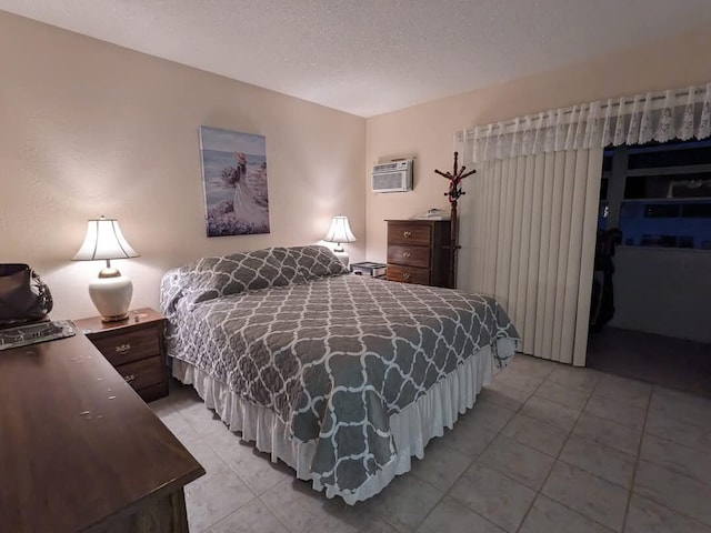 bedroom featuring a wall mounted AC, light tile patterned floors, and a textured ceiling