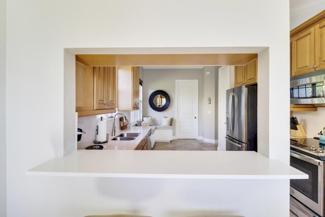 kitchen with stainless steel appliances, kitchen peninsula, sink, and light tile patterned floors