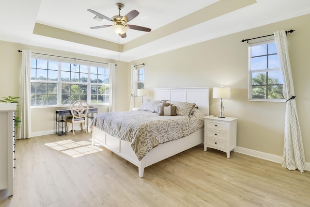 bedroom featuring a raised ceiling, ceiling fan, and light wood-type flooring