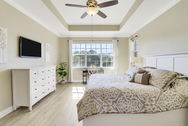 bedroom featuring ceiling fan, ornamental molding, a raised ceiling, and light wood-type flooring