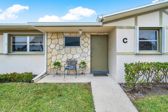 doorway to property with a lawn and a patio