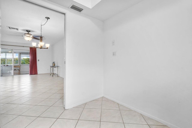 tiled empty room featuring ceiling fan with notable chandelier