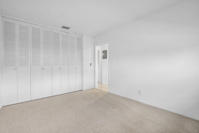 unfurnished bedroom featuring light colored carpet and a closet