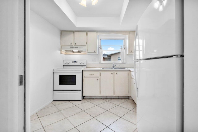 kitchen with light tile patterned floors, a raised ceiling, white appliances, cream cabinets, and sink