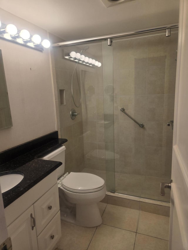 bathroom with tile patterned flooring, vanity, toilet, and walk in shower