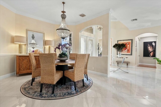 dining space with an inviting chandelier, crown molding, and french doors