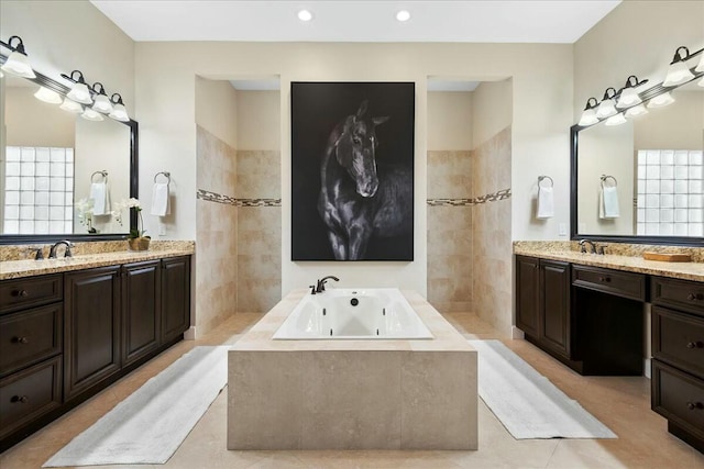 bathroom with tile patterned floors, tiled tub, and vanity