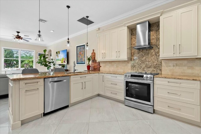 kitchen with ceiling fan, sink, wall chimney range hood, decorative light fixtures, and appliances with stainless steel finishes