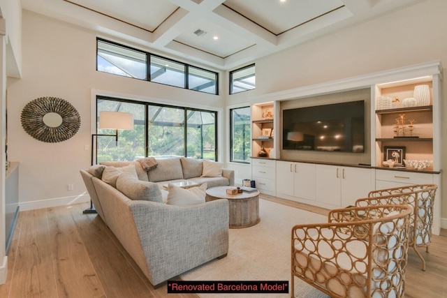 living room with coffered ceiling, beam ceiling, light hardwood / wood-style floors, and a towering ceiling