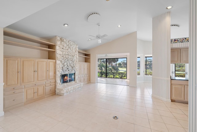 unfurnished living room featuring a fireplace, built in shelves, ceiling fan, light tile patterned floors, and high vaulted ceiling