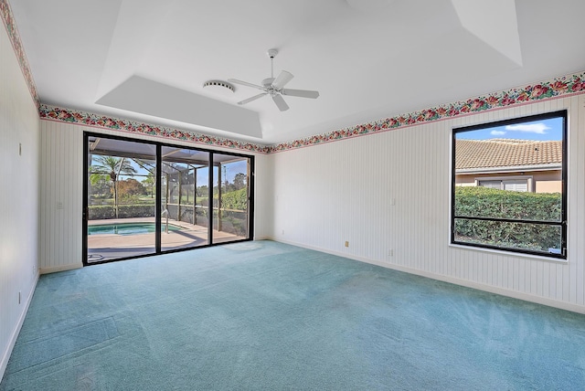 carpeted spare room featuring a tray ceiling and ceiling fan