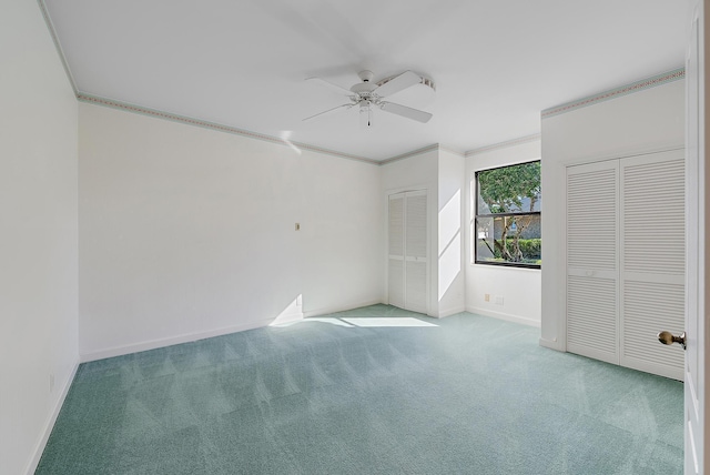 unfurnished bedroom with ornamental molding, light colored carpet, ceiling fan, and multiple closets