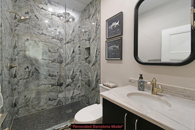 bathroom with vanity, tiled shower, and toilet