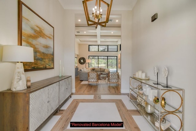 entryway with coffered ceiling, a chandelier, light wood-type flooring, a towering ceiling, and beam ceiling