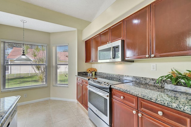 kitchen with appliances with stainless steel finishes, light tile patterned floors, light stone counters, and pendant lighting