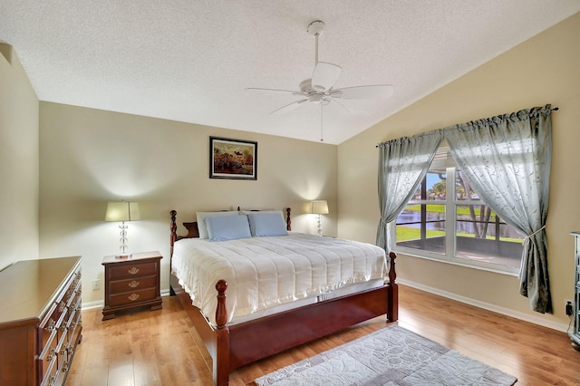 bedroom featuring a textured ceiling, ceiling fan, light hardwood / wood-style flooring, and vaulted ceiling