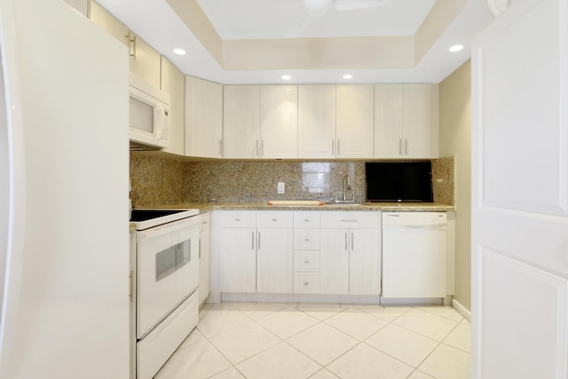 kitchen featuring white appliances, backsplash, a raised ceiling, light tile patterned floors, and light stone counters