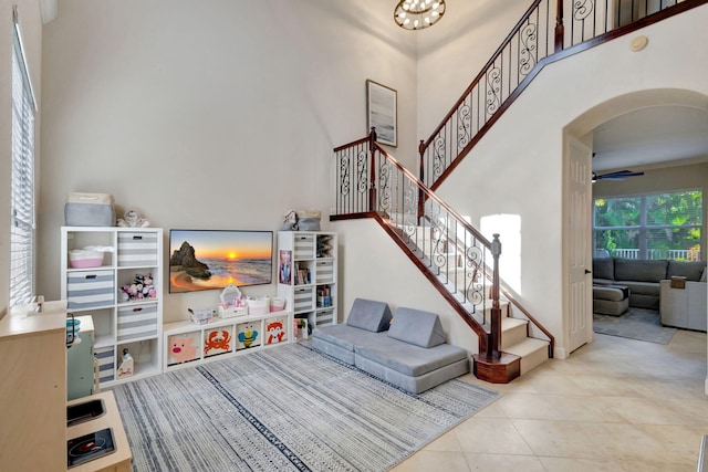 rec room featuring ceiling fan, a towering ceiling, and light tile patterned floors