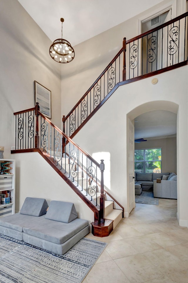 stairs with a notable chandelier and a towering ceiling