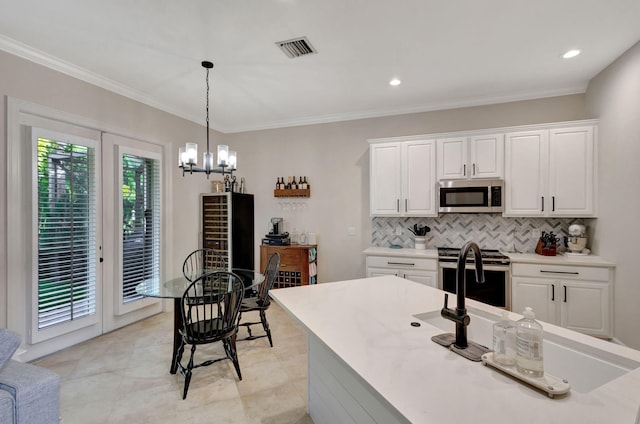 kitchen with pendant lighting, an inviting chandelier, decorative backsplash, appliances with stainless steel finishes, and white cabinetry