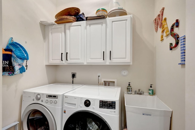 washroom with cabinets, washer and clothes dryer, and sink