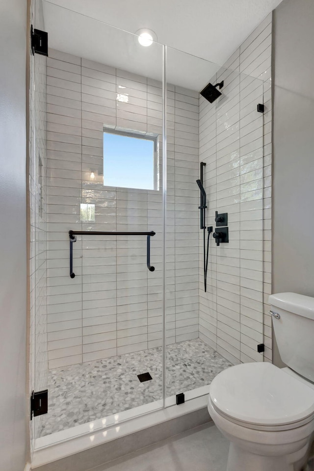 bathroom featuring toilet and a shower with shower door