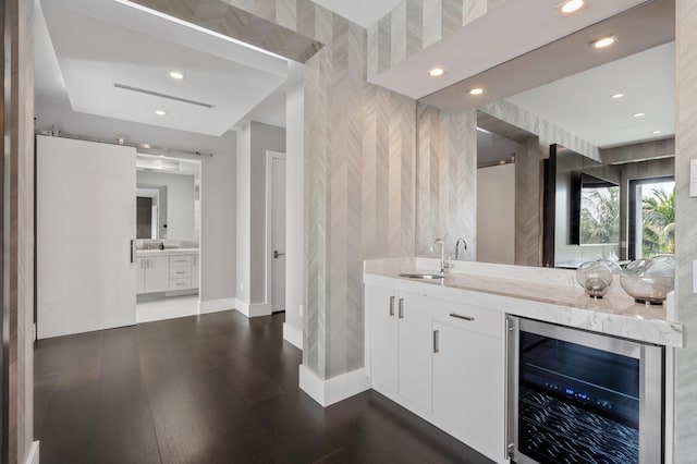 bar featuring light stone countertops, white cabinetry, beverage cooler, and sink