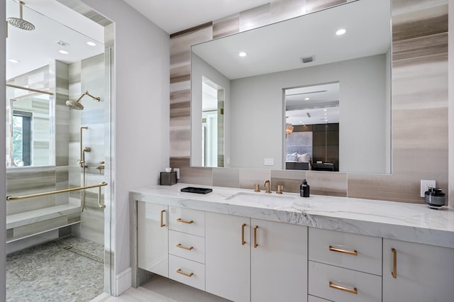 bathroom with a tile shower and vanity