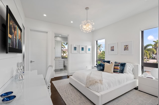 bedroom with a chandelier, connected bathroom, and hardwood / wood-style flooring