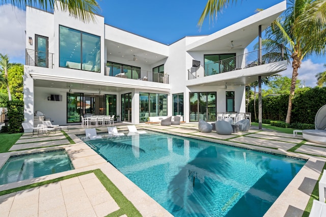 back of property featuring ceiling fan, a balcony, a patio, and a pool with hot tub