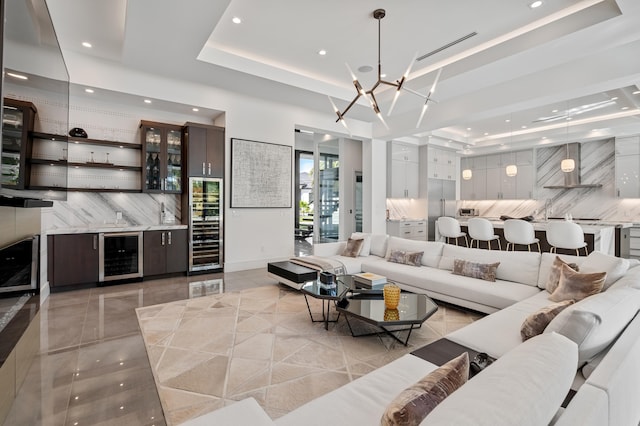 tiled living room featuring a tray ceiling, wine cooler, and a notable chandelier