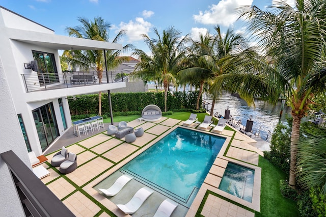 view of swimming pool with an in ground hot tub, a patio, a water view, and a lawn