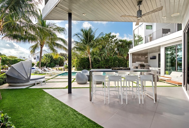 view of patio / terrace featuring a bar, a balcony, and ceiling fan