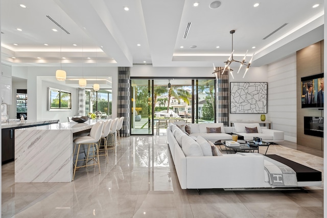 living room featuring a raised ceiling, a notable chandelier, and sink