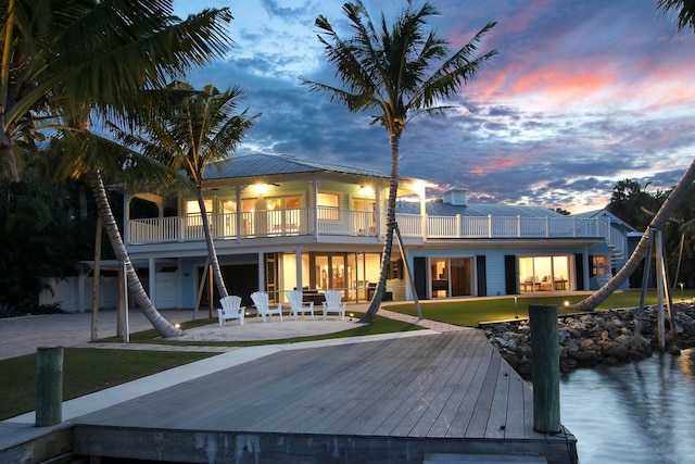 back house at dusk featuring a patio area and a balcony