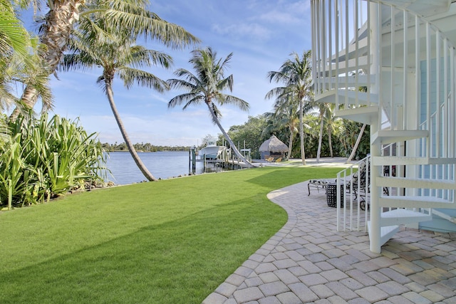 view of yard featuring a water view, a boat dock, and a patio