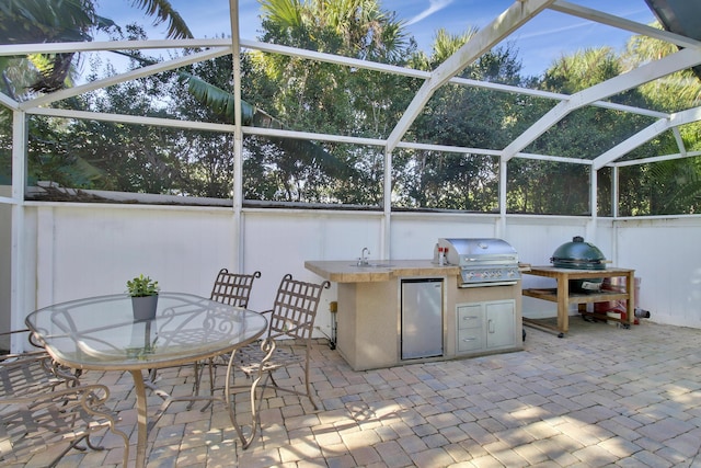 view of patio with glass enclosure, an outdoor kitchen, and area for grilling