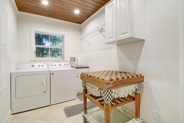 laundry area featuring wood ceiling, cabinets, washing machine and clothes dryer, ornamental molding, and light tile patterned floors