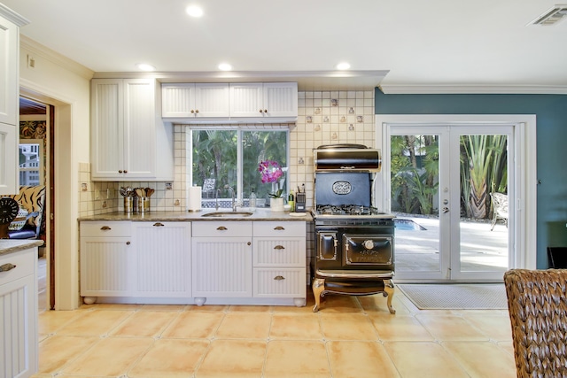 kitchen with tasteful backsplash, sink, white cabinets, french doors, and stone countertops