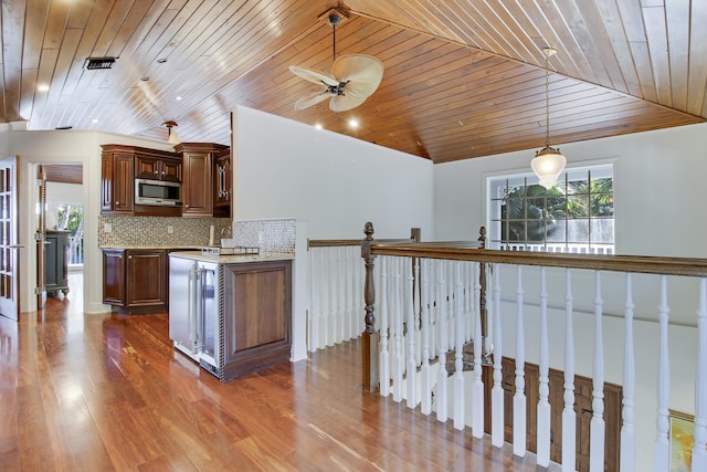 kitchen with stainless steel microwave, vaulted ceiling, hardwood / wood-style floors, decorative backsplash, and wooden ceiling